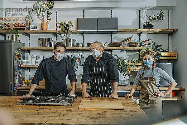 Chefs wearing protective face mask staring while standing in kitchen