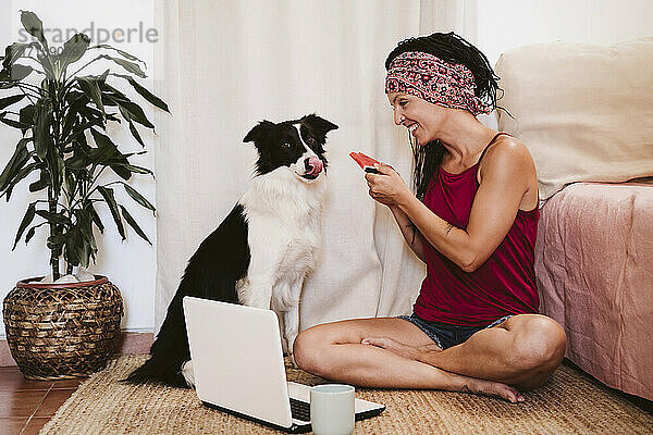 Frau füttert Haustier mit Wassermelone  während sie zu Hause am Laptop sitzt