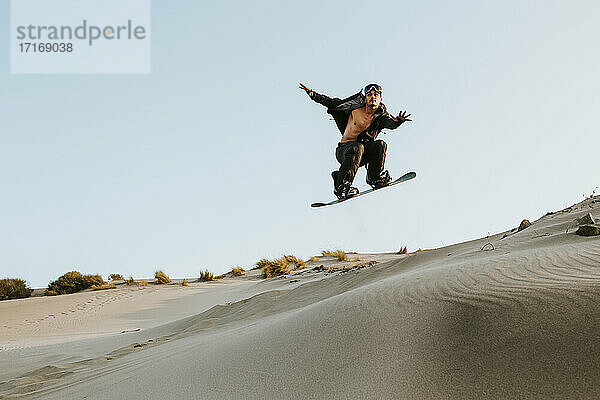 Junger Mann  der einen Stunt beim Standboarding in Almeria  Tabernas-Wüste  Spanien  durchführt