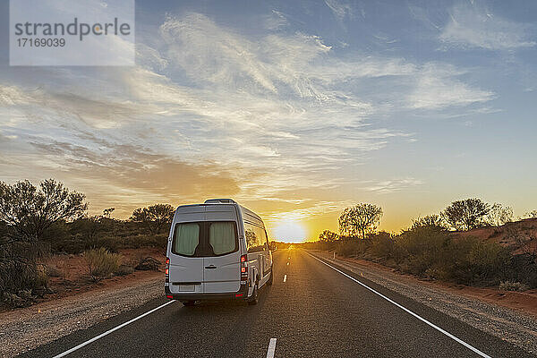 Van driving along Lasseter Highway at sunrise  Australia