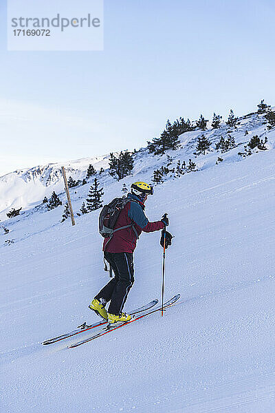 Mature male skier climbing on snowy mountain