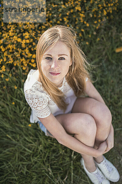 Schöne blonde Frau sitzt auf einem landwirtschaftlichen Feld