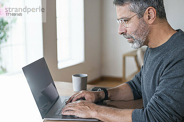 Geschäftsmann konzentriert sich bei der Arbeit am Laptop im Büro zu Hause sitzend