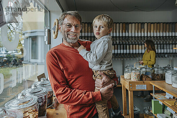 Älterer Vater trägt seinen Sohn in einem Lebensmitteleinzelhandelsgeschäft