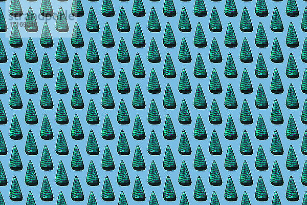 Muster aus baumförmigen Bonbons vor hellblauem Hintergrund