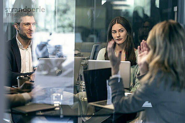 Businesswoman discussing with colleague while sitting in meeting at office
