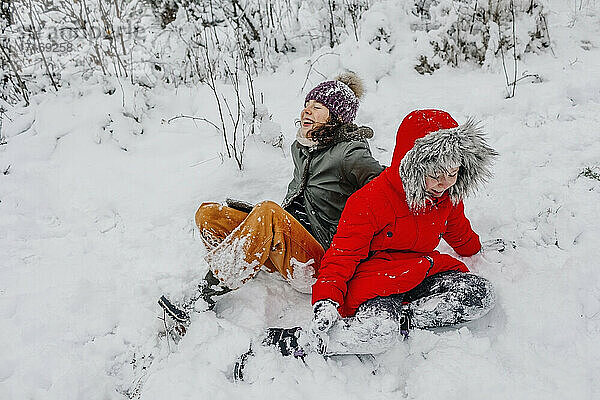 Fröhliche Schwestern beim Spielen im Schnee im Winter