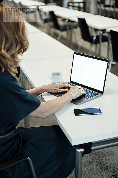 Unternehmerin tippt auf einem Laptop im Sitzungssaal eines Büros