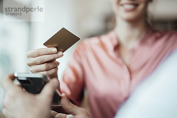 Weibliche Kundenhand  die mit Kreditkarte an den männlichen Besitzer eines Cafés zahlt