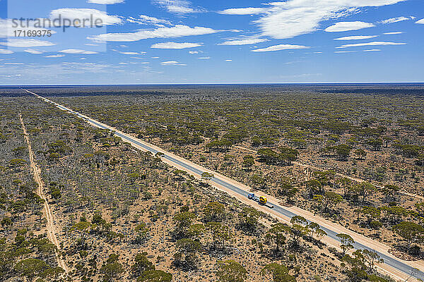 Luftaufnahme des Eyre Highway  der sich über den Nullarbor National Park erstreckt  mit einer klaren Horizontlinie im Hintergrund