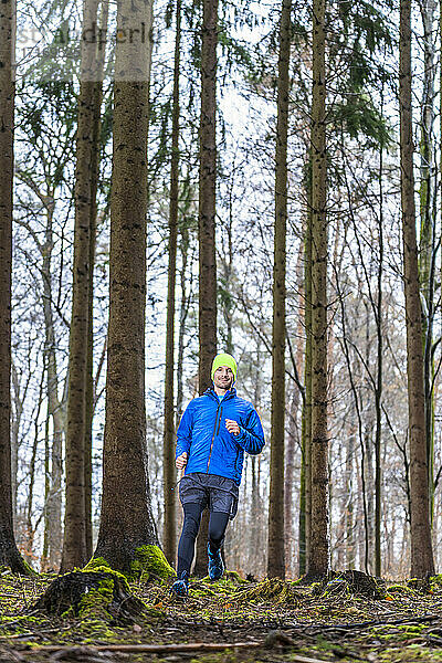 Mann joggt auf einem Pfad inmitten von Nadelbäumen im Wald