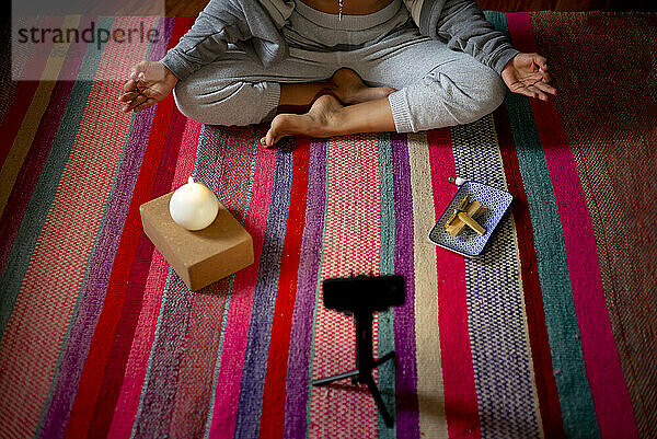 Spiritual woman meditating during video call at home