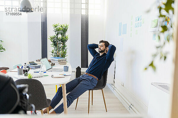Relaxed male entrepreneur with eyes closed sitting in office