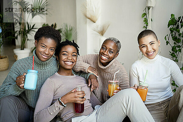 Happy female friends having juice in living room