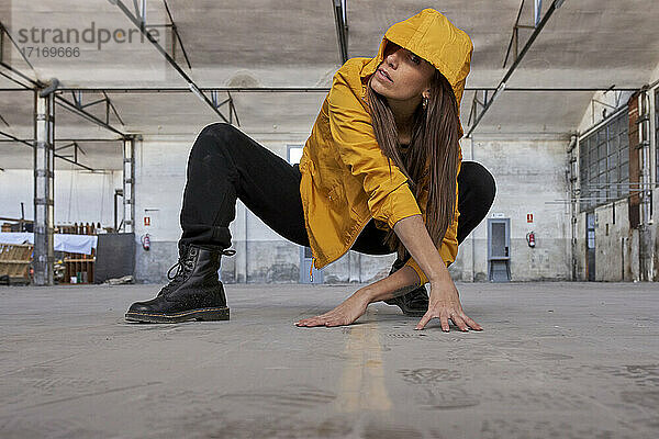 Modern dancer in yellow jacket practicing dance at abandoned factory