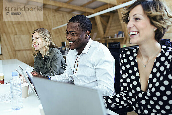 Lächelnde Geschäftskollegen am Schreibtisch in einem Coworking-Büro