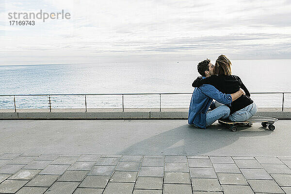 Paar auf dem Boden sitzend in einem Skateboard  mit Blick auf das Meer