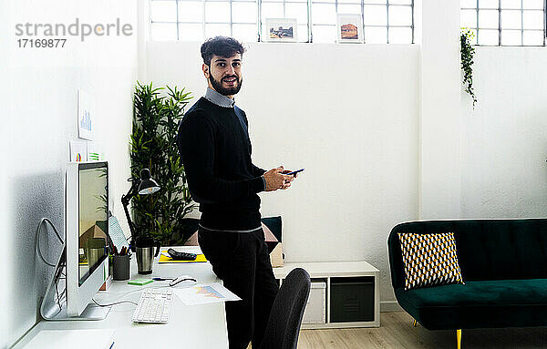 Porträt eines Geschäftsmannes mit Smartphone am Schreibtisch im Büro