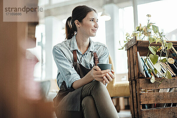 Lächelnde Managerin mit Kaffeetasse  die in einem Café wegschaut