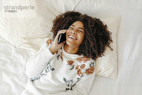 Junge Frau lächelt  während sie zu Hause mit dem Handy telefoniert