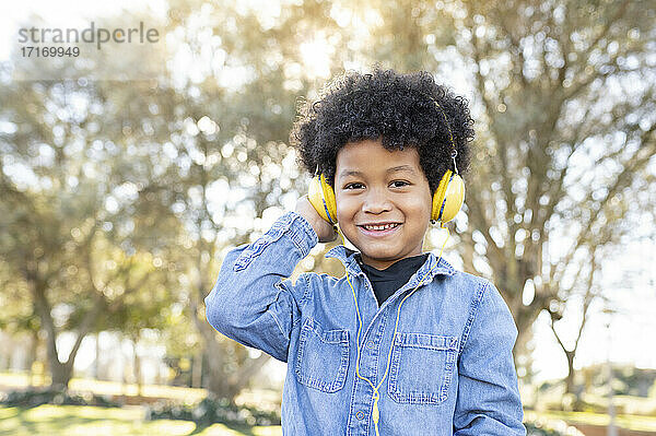 Junge hört Musik über Kopfhörer  während er im Park sitzt