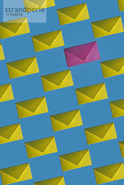Muster aus Reihen gelber Umschläge mit einem einzelnen rosa Umschlag