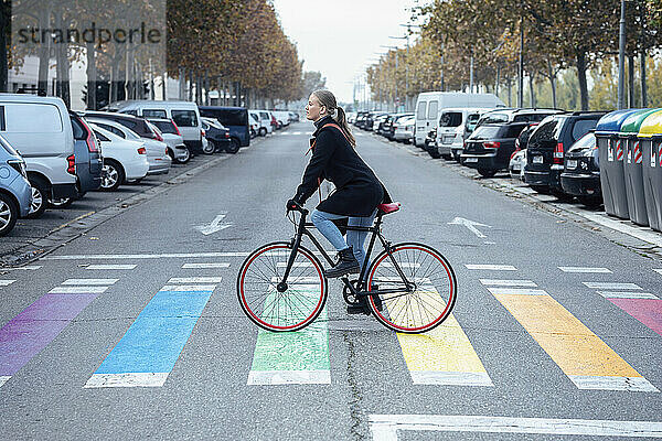 Woman cycling on multi colored zebra crossing