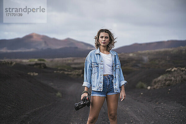 Junge Frau steht mit Kamera auf dem Fußweg am Vulkan El Cuervo  Lanzarote  Spanien
