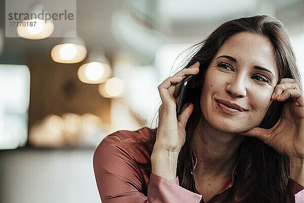 Lächelnde weibliche Fachkraft beim Telefonieren im Café