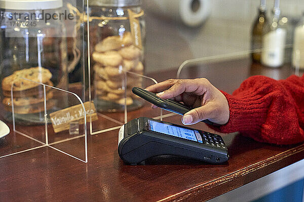 Woman paying through mobile phone at coffee shop