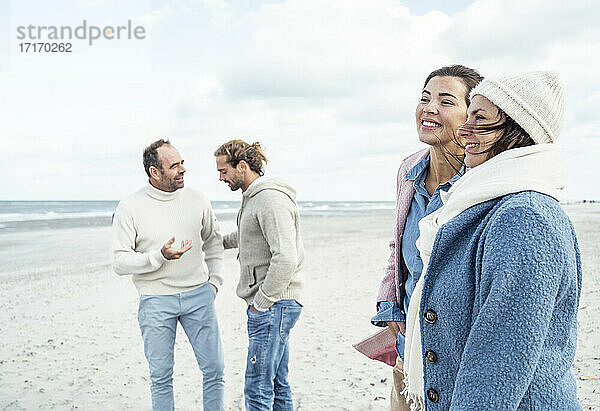 Gruppe erwachsener Freunde  die am Küstenstrand stehen und sich unterhalten