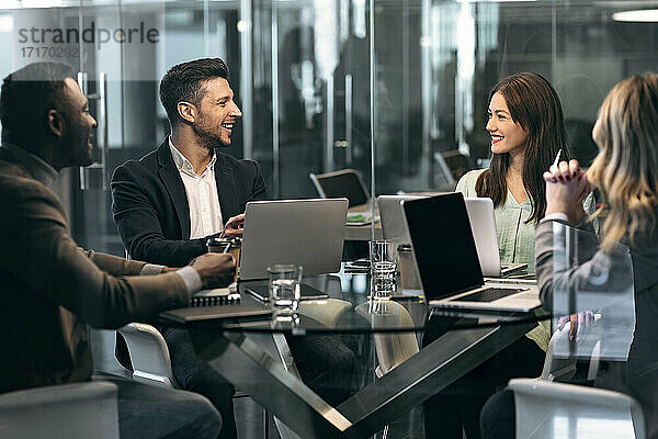 Smiling business people having discussion in meeting while sitting at office
