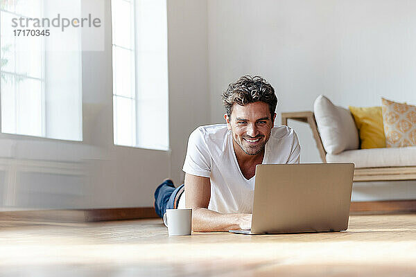 Mann lächelnd bei der Arbeit am Laptop zu Hause