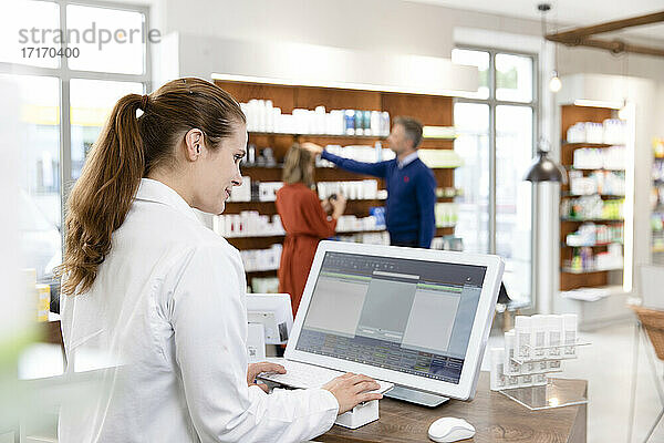 Female pharmacist using computer at checkout in store