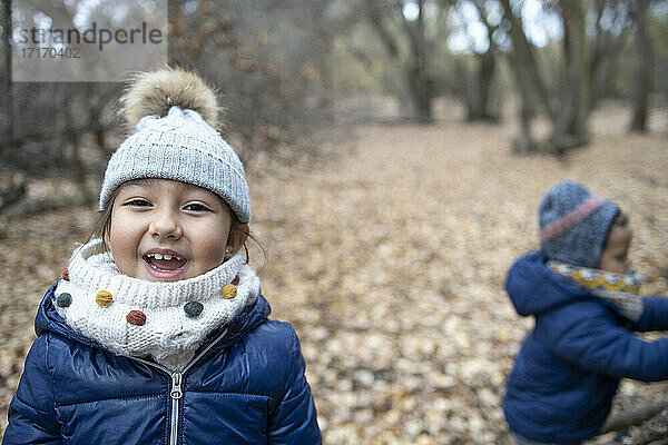Nettes Mädchen mit Bruder genießt im Wald im Herbst