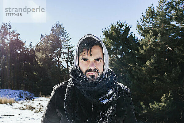 Bearded man in warm clothing standing on snow covered land against sky