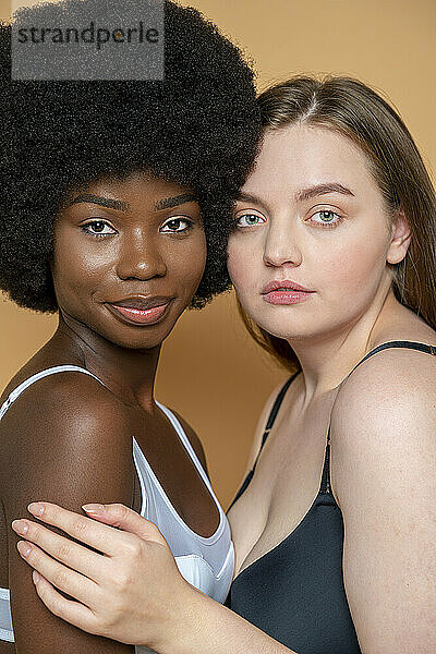Schöne multiethnische weibliche Modelle in Dessous vor gelbem Hintergrund