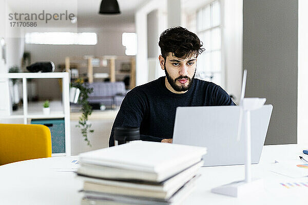 Junger Geschäftsmann mit Laptop im Kreativbüro