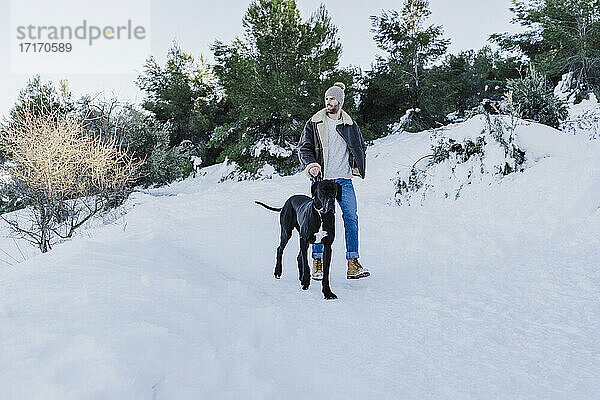 Junger Mann und Hund wandern im Winter im Schnee