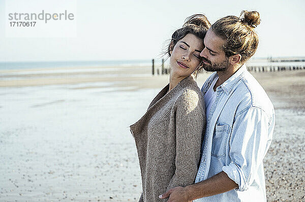 Zärtliches junges Paar am Strand an einem sonnigen Tag am Wochenende