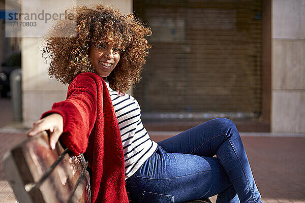 Young woman smiling while sitting on bench