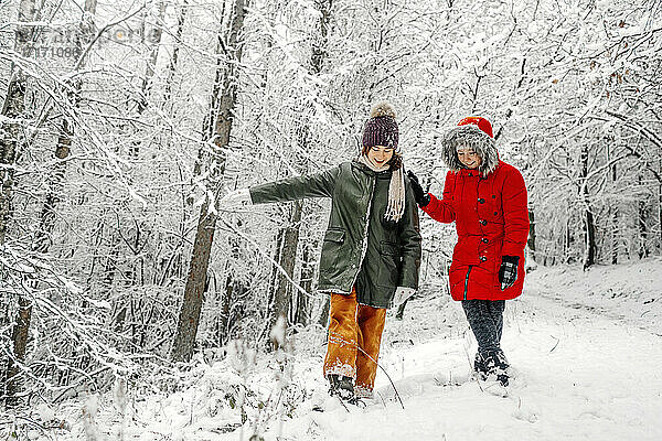 Teenager-Mädchen mit Schwester spazieren auf Schnee im Wald im Winter