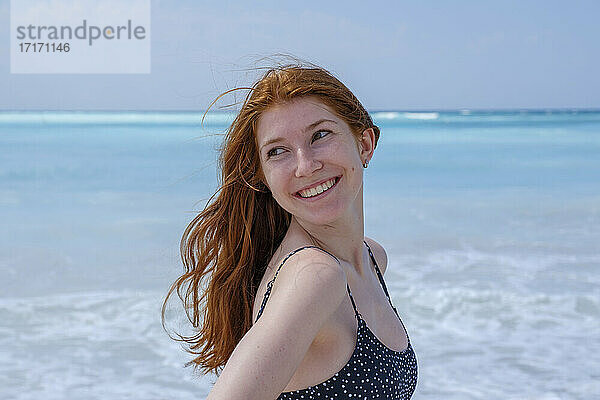 Lächelnde Frau  die wegschaut  während sie am Meer steht