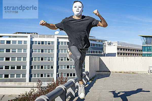 Mann mit Maske läuft an einem sonnigen Tag auf einem Dach