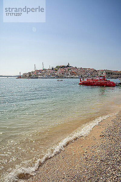 Rotes U-Boot am Strand vor dem Stadtbild von Primosten in Sibenik-Knin  Kroatien