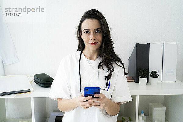 Ärztin hält Smartphone in der Klinik
