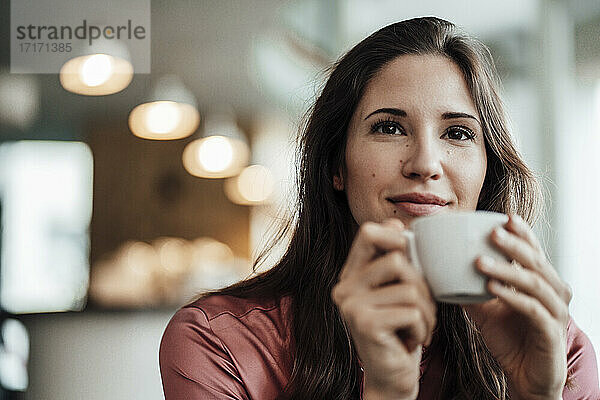 Unternehmerin mit Kaffeetasse und Tagträumen in einem Café