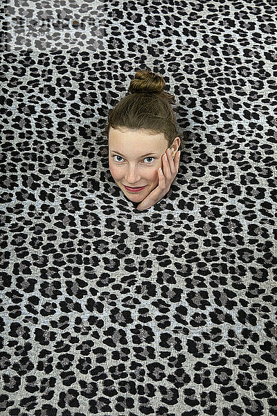 Studio shot of head of teenage girl sticking out of leopard print