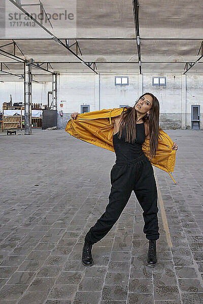 Modern female dancer in yellow jacket at abandoned factory