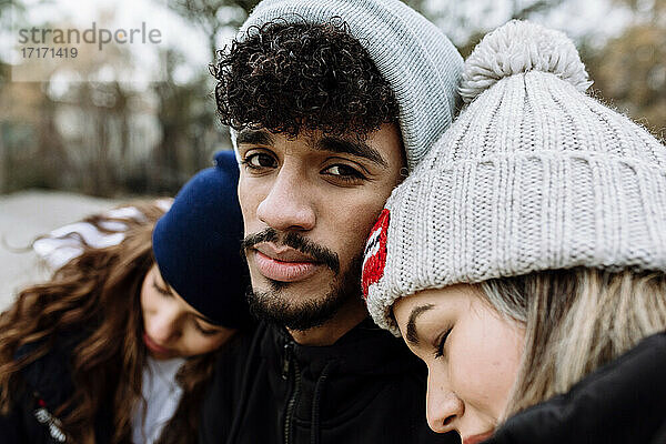 Female friends leaning on male friend shoulder at park